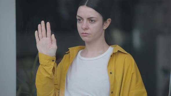 Live Camera Moves Down Unhappy Pregnant Young Woman Looking Out Window with Hand on Glass