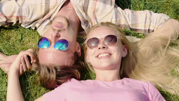 Happy Young Couple Enjoying Weekend, Lying on Lawn and Talking, Summertime