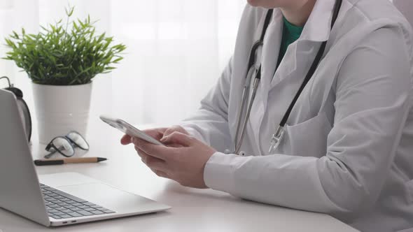 Doctor Hands Using Mobile Phone Device Sitting on Doctor's Office Working Desk