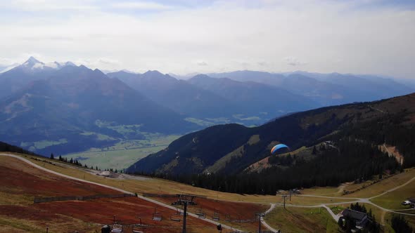 Paraglider Passes By The Gondola Tower At The Schmittenhohe Mountain In Salzburg, Austria. aerial