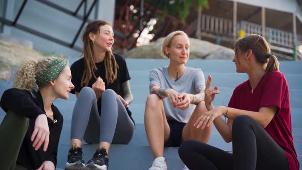 Group of Four Young Women, Best Friends Sitting Outdoor and Talking.