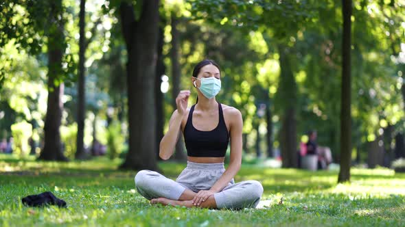 A Happy Woman in the Park Takes Off the Protective Face Mask