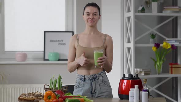 Happy Confident Beautiful Slim Woman Gesturing Thumb Up Smiling Posing with Healthful Green Smoothie