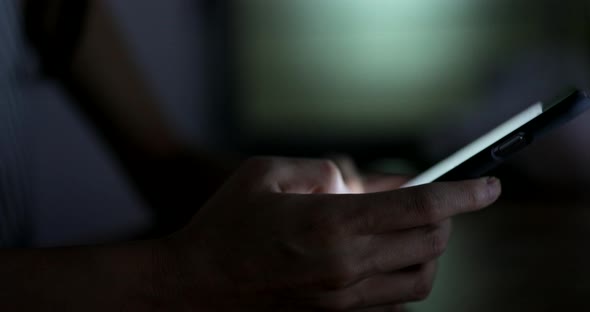 Woman using cellphone in the living room at night