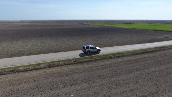 Car Going on The Road Between Green and Brown Fields