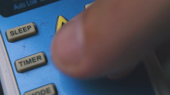 Person Presses Buttons on Air Conditioner Remote Macro