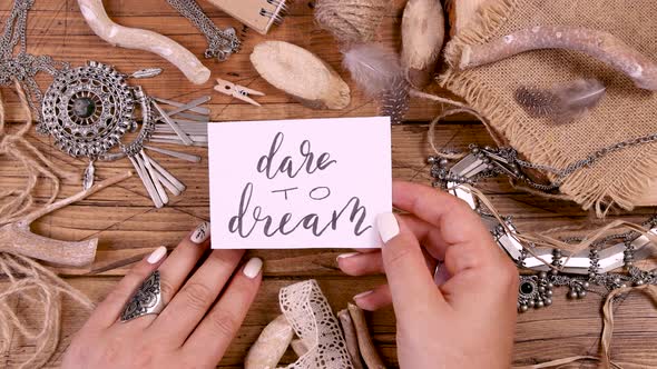 Hand with DARE DO DREAM card over a wooden table top view