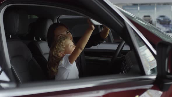 Happy Mother and Daughter Discussing Interior of Car in Auto Showroom