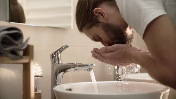 Morning Hygiene. Man Washing Face With Clean Water At Bathroom