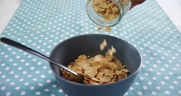 Hands spilling wheat corn flakes into bowl 4k