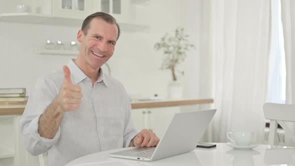 Positive Middle Aged Man with Laptop Doing Thumbs Up 