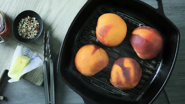 Grilling organic peaches in cast iron skillet.
