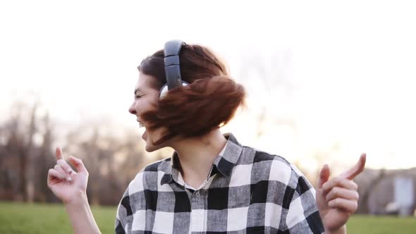 A Girl with Brown Hair is Very Emotionally and Expressively Waving Her Head Listening to Music on