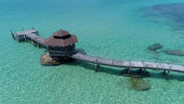 Aerial of gazebo on a dock out in the ocean on the rocks.