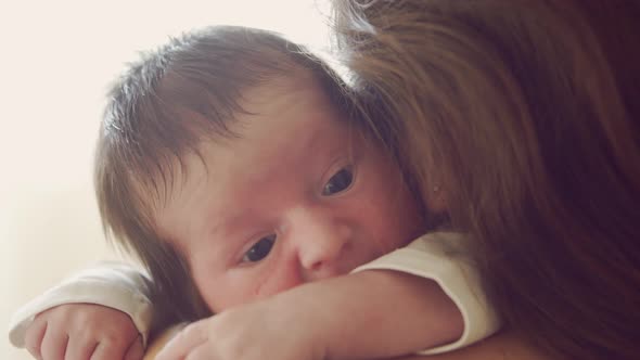 Newborn baby boy and his mother at home. Close-up portrait of the infant