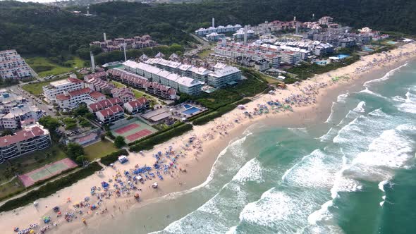 Aerial view of tropical tourist beach with hotels and summer houses facing the sea with many people