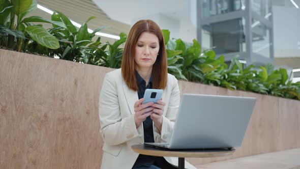 Businesswoman Texting Message on Phone in Cafe