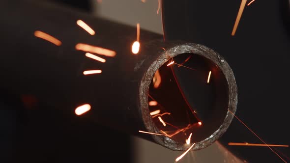Metal Pipe is Sawed Using an Angle Grinder and Cutting Disc Sparks Fly Out Closeup