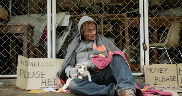 Homeless holding and playing with cat