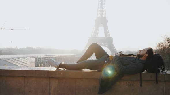 Relaxed Happy Male Tourist Lying Down with Eyes Closed at Amazing Sunset Eiffel Tower View in Paris