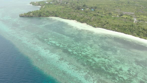 Aerial: Flying over tropical beach turquoise water coral reef , Indonesia