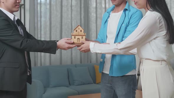 Asian Real Estate Agent Giving A House Model To A Couple