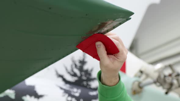 Man in a Green Sweatshirt Glues Inscription NO PUSH on Wing of Helicopter