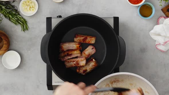 Crop person cooking ribs on pan