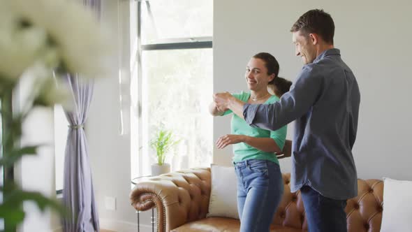 A young happy caucasian couple in love talking and dancing at home