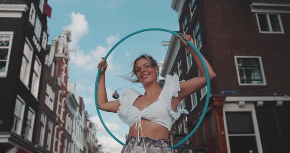 Woman holds Hula Hoop overhead and smiles