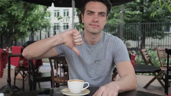 Thumbs Down By Man Sitting in Cafe Terrace Window