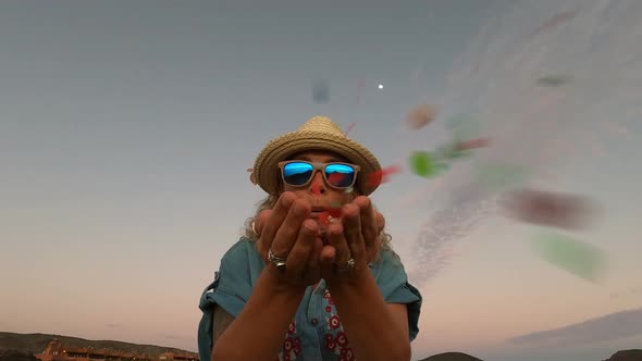 Happy woman blowing confetti from her hands