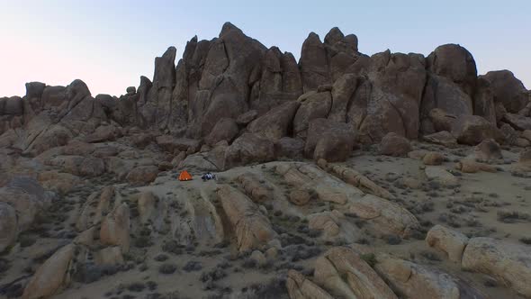 Aerial shot of a young man backpacker camping with his dog in a mountainous desert