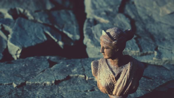 Ancient Statue of Woman on Rocky Stones alt