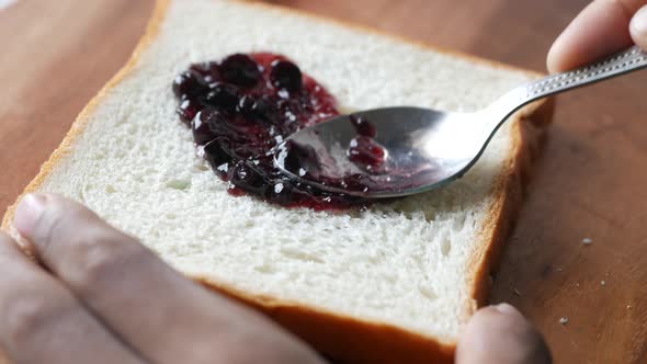 Spreading Blue Berry Jam on Bread on Table