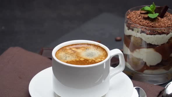 Classic Tiramisu Dessert in a Glass and Cup of Coffee on Dark Concrete Background