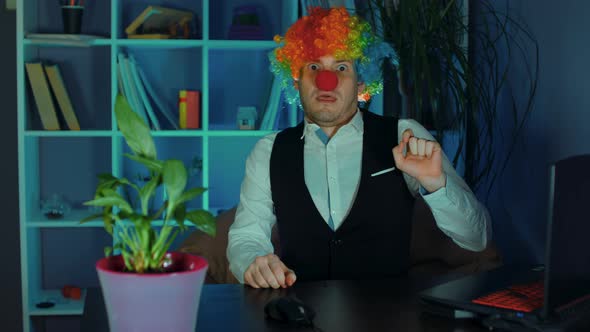 Young Man in Image of Clown Afraid of Laptop in Office