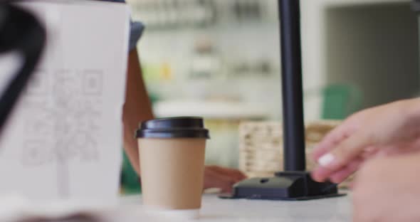 Video of hands of biracial waitress serving coffee and holding payment terminal