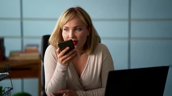 Woman Is Talking on Speakerphone By Cell Phone at Office, Sending Voice Message