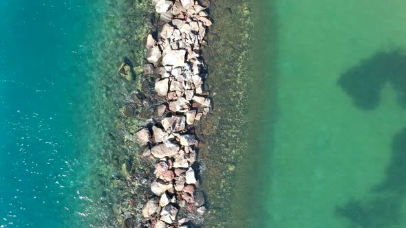 Aerial view of two different bodies of water divided by a man made break wall