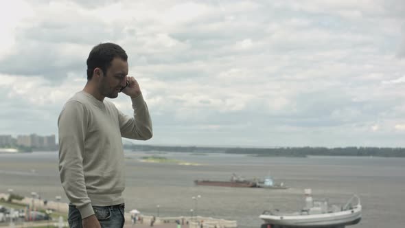 Handsome Man Included in the Frame and Talking on a Smart Phone Near River