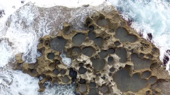 Volcanic built coastline of Nusa Penida island near Broken beach hit by strong waves, Aerial top vie