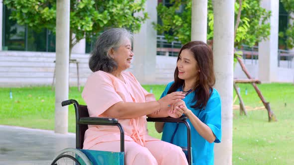 Asian careful caregiver or nurse taking care of the patient in a wheelchair.  Concept of happy retir