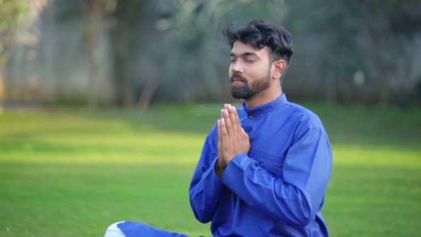 Indian man doing Namaste Yoga pose or Namaskarasana in an Indian traditional outfit Kurta Pajama