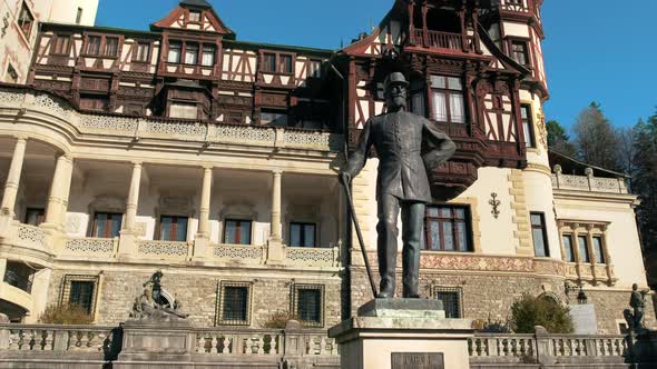 King Carol statue at The Peles Castle in Romania. Castle on the background