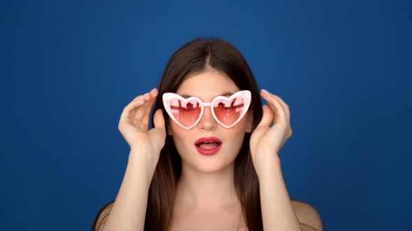 Portrait of a Beautiful Girl in Pink Glasses on a Blue Background