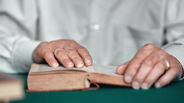 Elderly Grandfather Wrinkled Hands Reading Book at Library on Desk Closeup