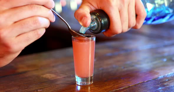 Barman mixing color in tequila at bar counter