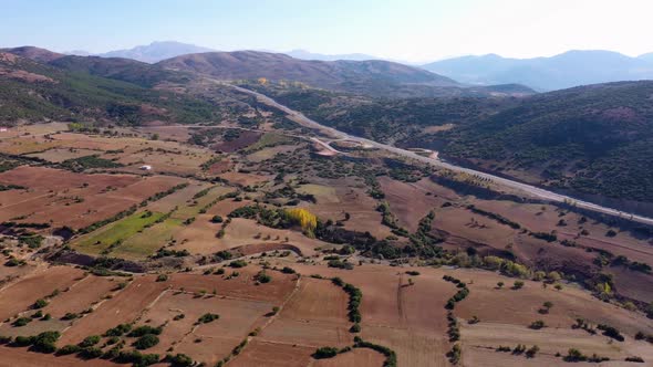 Panoramic Aerial View of Mountain Valley with Farmlands and Road