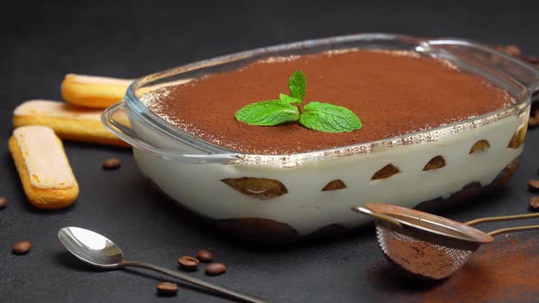 Tiramisu Dessert in Glass Baking Dish and Savoiardi Cookies on Concrete Background